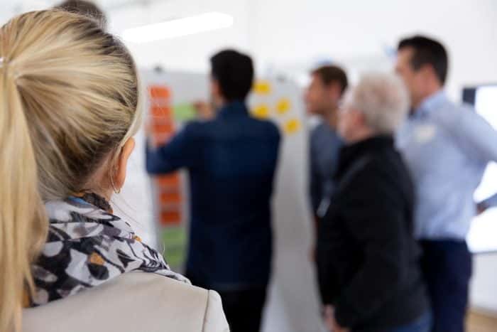 Kunden von Me & Company arbeiten im Hintergrund am Whiteboard im Rahmen des Zukunftsträger Programms