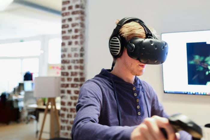 Mitarbeiter von Me & Company spielt ein VR-Spielt und trägt die HTC Vive
