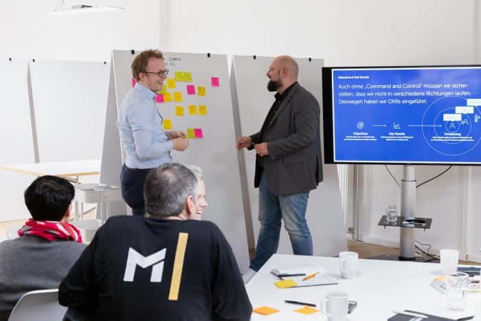Mitarbeiter von Me & Company steht zusammen mit Kunden der Metro AG vor Whiteboard