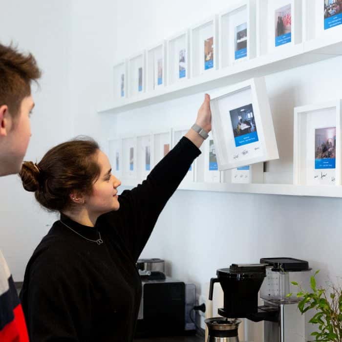 Mitarbeiterin von Me & Company hält in ihrer Rolle als Team Support Bilderrahmen in der Hand