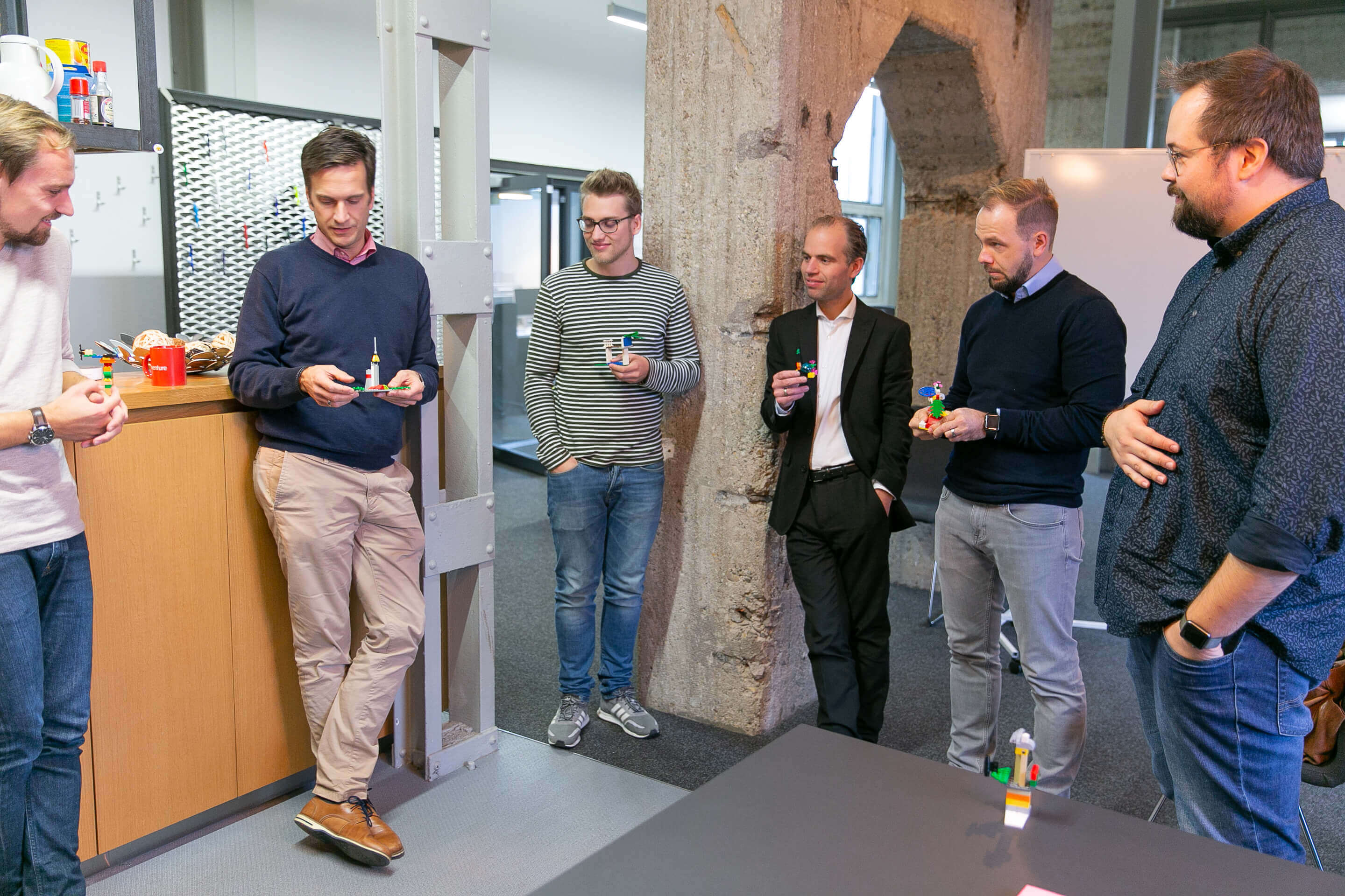 Workshop-Teilnehmer stehen bei einer Warm-Up Übung zusammen und stellen ihre Lego-Figuren vor