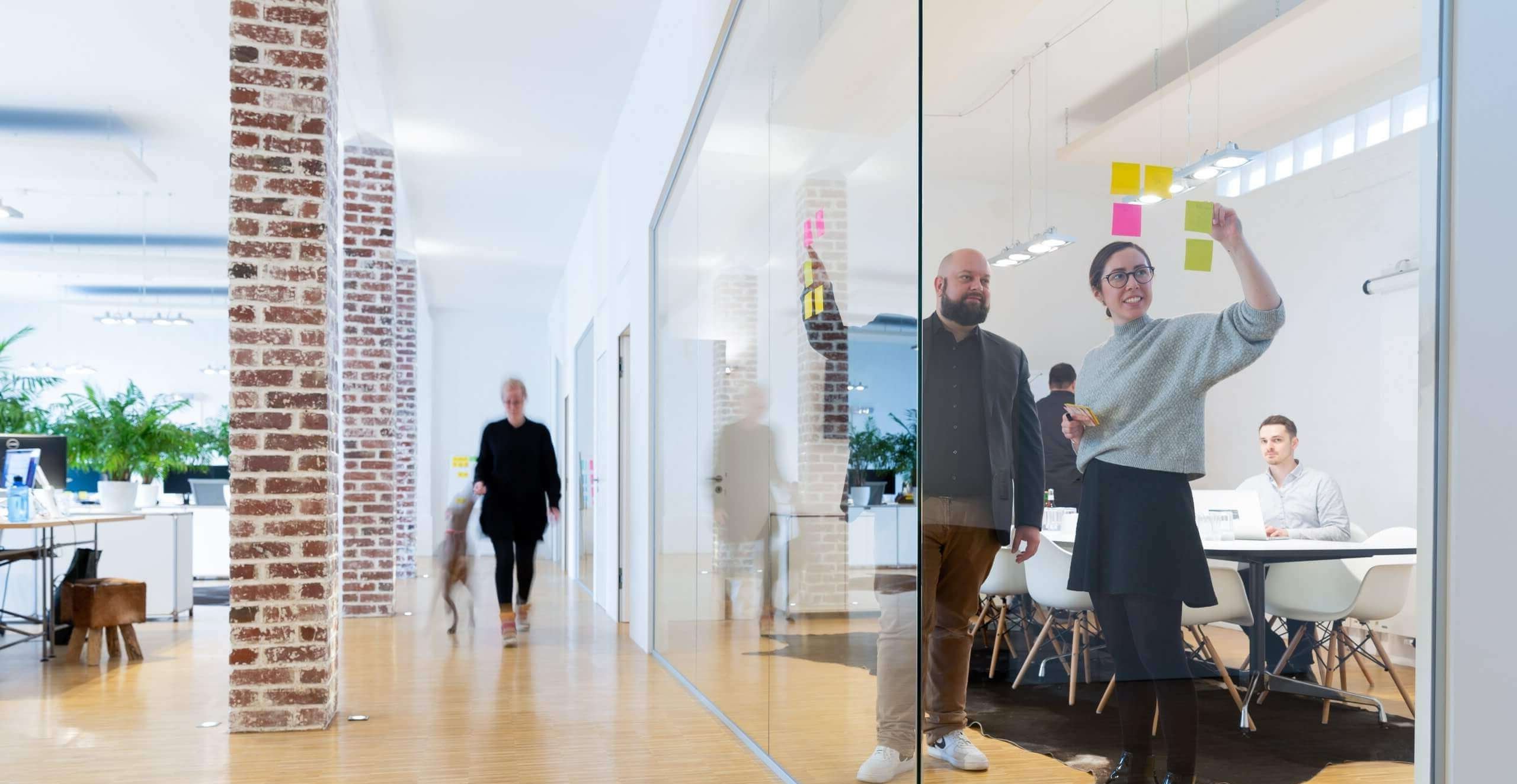 Großraumbüro einer Innovationsberatung mit Menschen die zusammenarbeiten.