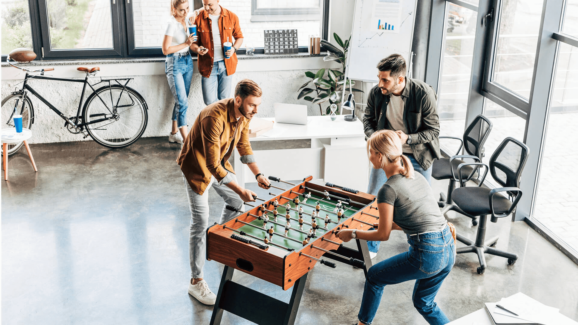 Menschen spielen Kicker in einem modernen Büroraum