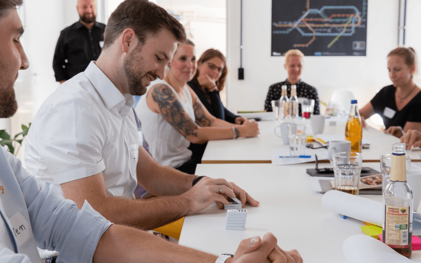 Menschen sitzen um einen Tisch und schreiben auf Post-Its