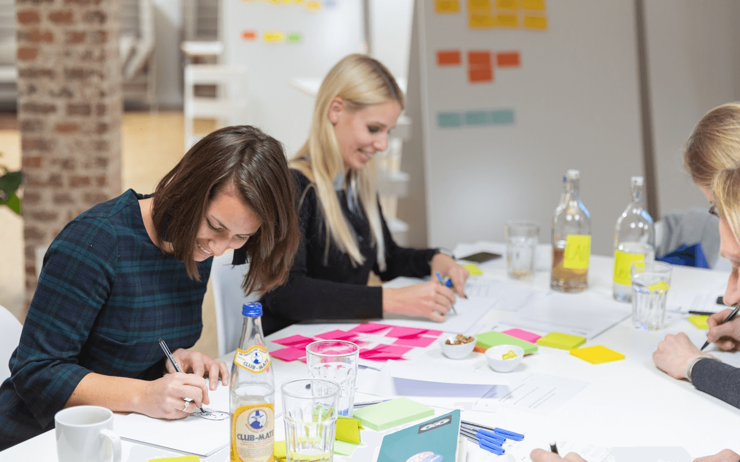 Drei Frauen sitzen an einem Tisch und zeichnen.
